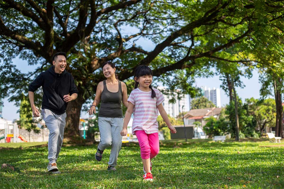 Mom and dad chasing child at shaded park